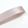 A roll of double face satin ribbon in a light mauve color shown diagonally.