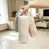 A hand is holding a quilted cotton storage bag for a hair dryer, showing various fabric patterns.