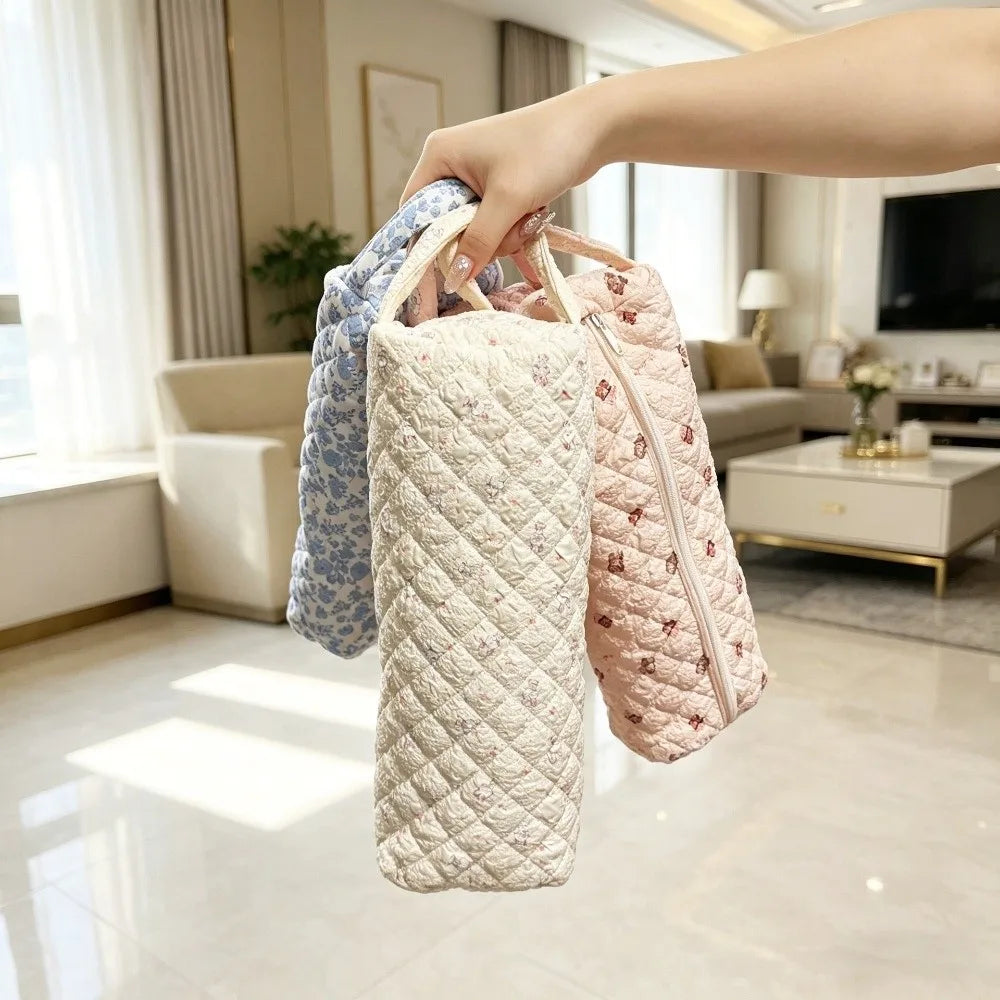 A hand is holding a quilted cotton storage bag for a hair dryer, showing various fabric patterns.
