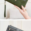 A close-up of a red and green PU leather long wallet being held by a hand.