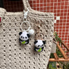 A light beige crochet tote bag with a white pendant featuring a black and white panda charm.
