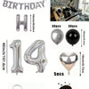 A kit featuring silver and black foil balloons, including large numbers, heart shapes, and a bulk of dark brown confetti.