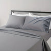 A gray microfiber bed sheet set with white linens is displayed on a bed with a dark headboard.