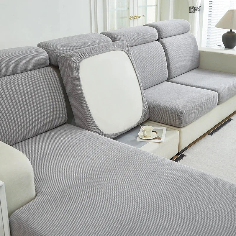 A light gray elegant stretch sofa slipcover with white cushions and a textured fabric.
