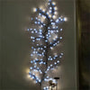 A vertical arrangement of blue LED lights shaped like a cherry blossom branch against a light gray wall.