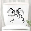 White toilet lid featuring a black sticker of an expressive, surprised face with water droplets.