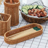 A collection of handwoven wicker serving baskets and bamboo chopsticks displayed on a white checkered surface.