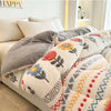 A close-up of a beige and gray plush throw blanket with floral and geometric patterns on a bed.