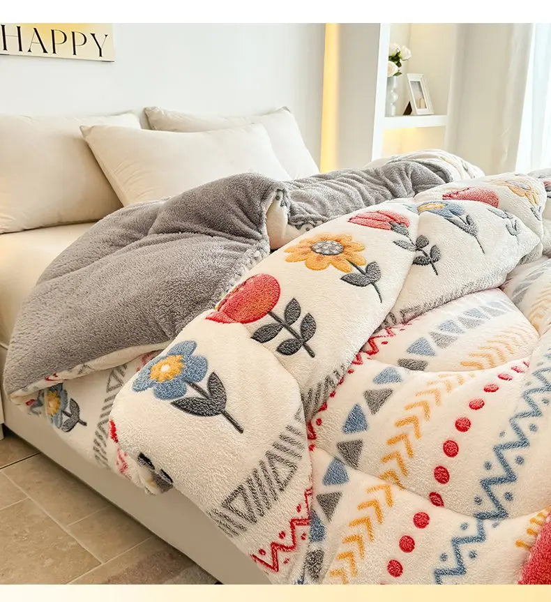 A close-up of a beige and gray plush throw blanket with floral and geometric patterns on a bed.