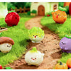 A collection of hand-painted resin vegetable figurines, including a strawberry, pumpkin, mushroom, and various green and yell