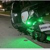 A black motorcycle is parked on the side of a road with green strobe lights illuminating the pavement.