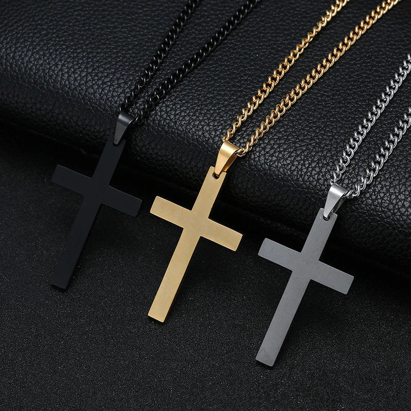 Three stainless steel cross pendant necklaces in black gold and silver tones displayed on a black surface.