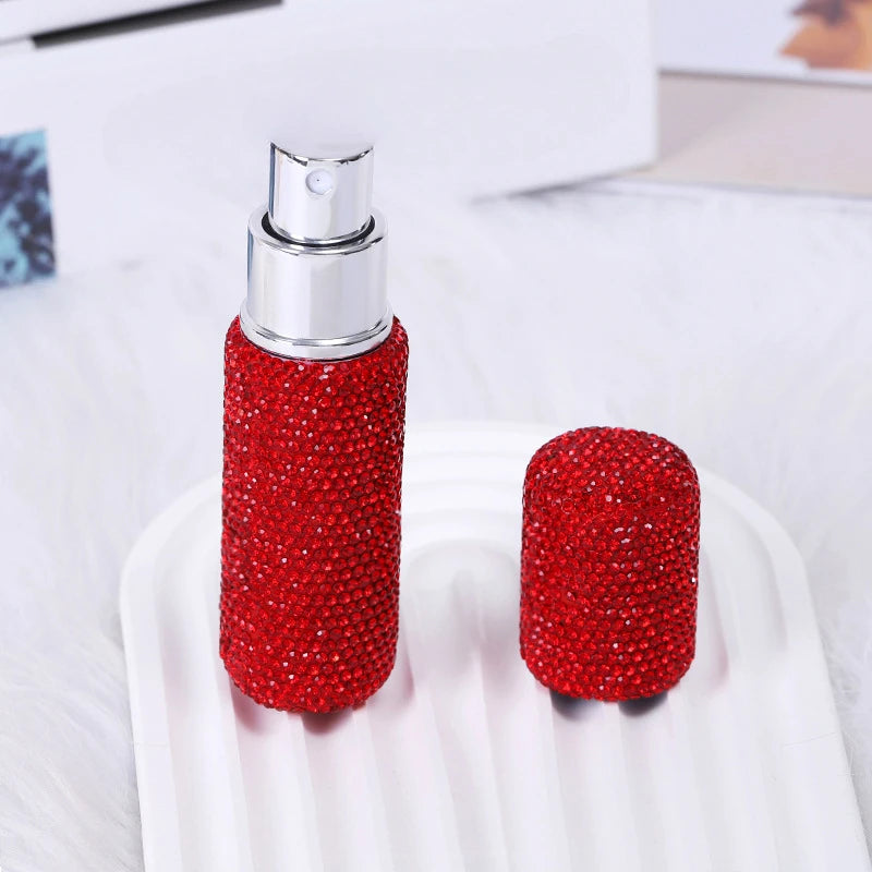 A red textured glass perfume atomizer bottle with a silver cap resting on a white tray.