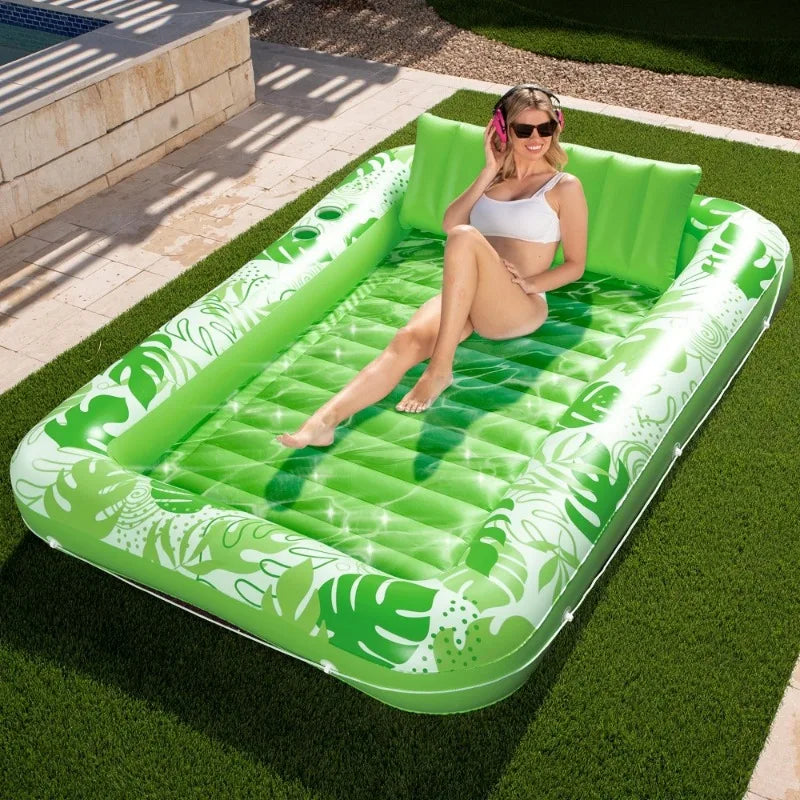 Une femme se relaxe sur un transat gonflable vert vif à une piscine extérieure sur une pelouse.