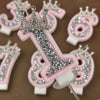 A collection of pink and white rhinestone crown number candles for birthday cakes, including the numbers 3, 6, and 9.