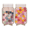 A wooden jar filled with colorful wooden flowers and stars used as a reward jar for positive behavior.
