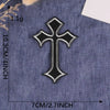A black embroidered cross patch on a dark blue denim fabric.