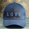 A dark blue denim baseball cap featuring the word LOVE embroidered on the front.