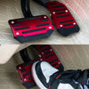 A set of red and black universal car pedal covers installed on a vehicle's pedals.