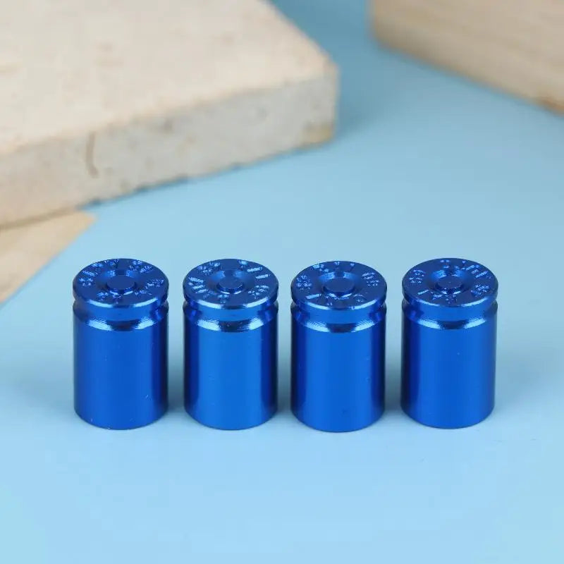 A set of four bright blue bullet shell tire valve stem caps resting on a light blue surface.