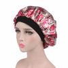 A woman wearing a floral patterned satin hair bonnet with a black elastic band.