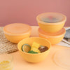 A set of bright orange airtight storage bowls and lids displayed on a wooden surface.