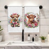 A set of two white kitchen towels featuring a watercolor illustration of a cute Highland cow's head with pink flowers.