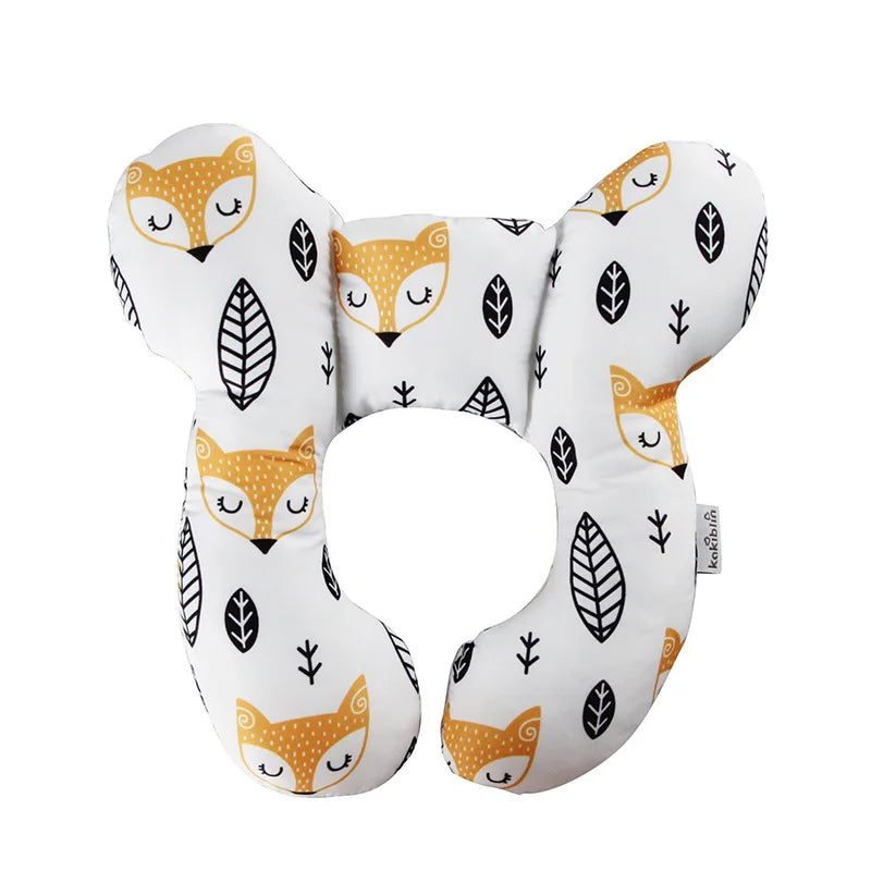 A white baby head and neck support pillow featuring cute orange fox faces and leaf patterns.