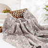 A soft, gray muslin baby swaddle blanket with a floral pattern is draped on a white surface.