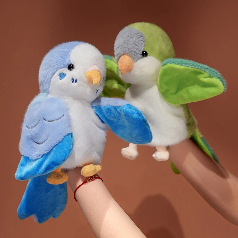 A pair of fluffy plush parrot hand puppets featuring blue and green feathers being held by a person's hand.