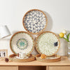 Handcrafted rattan serving tray with mother of pearl inlay featuring decorative plates and a small loaf of bread.