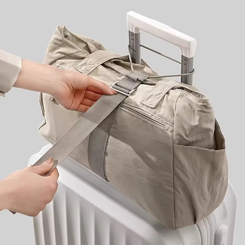 A hand is adjusting an adjustable luggage strap with a quick-release buckle on a beige backpack.