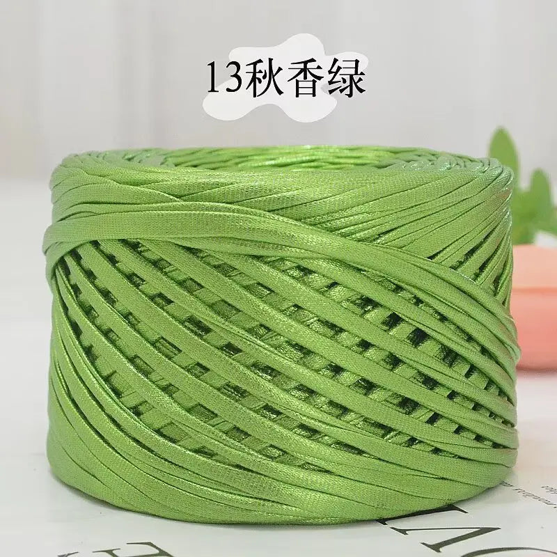 A spool of metallic green flat ribbon yarn for crochet and knitting.