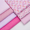 A collection of pink cotton quilted fabric strips featuring various floral and polka dot patterns.