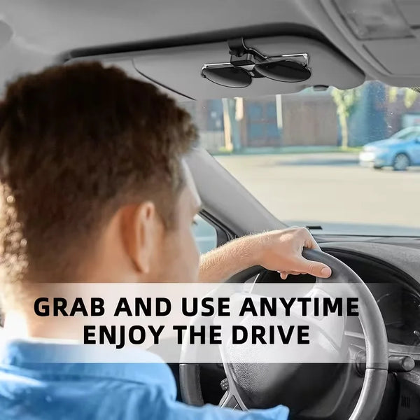 A person is driving a car, and the image shows a car visor with a clip holder for sunglasses or glasses.