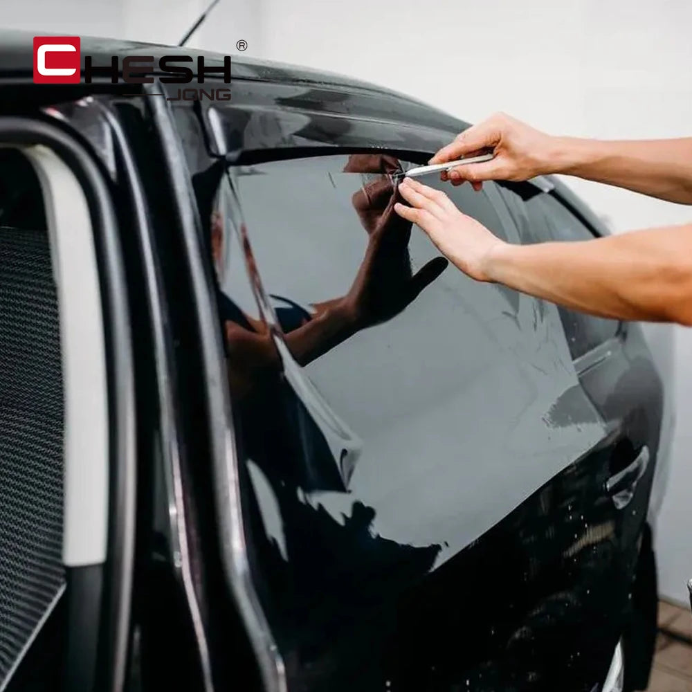 A hand is applying a premium car window tint film to the glass of a black car.