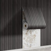 A roll of wood grain peel-and-stick wall tiles is partially unrolled against a dark vertical slat wall.
