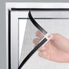 A hand is installing a black magnetic window mosquito net into a white window frame.