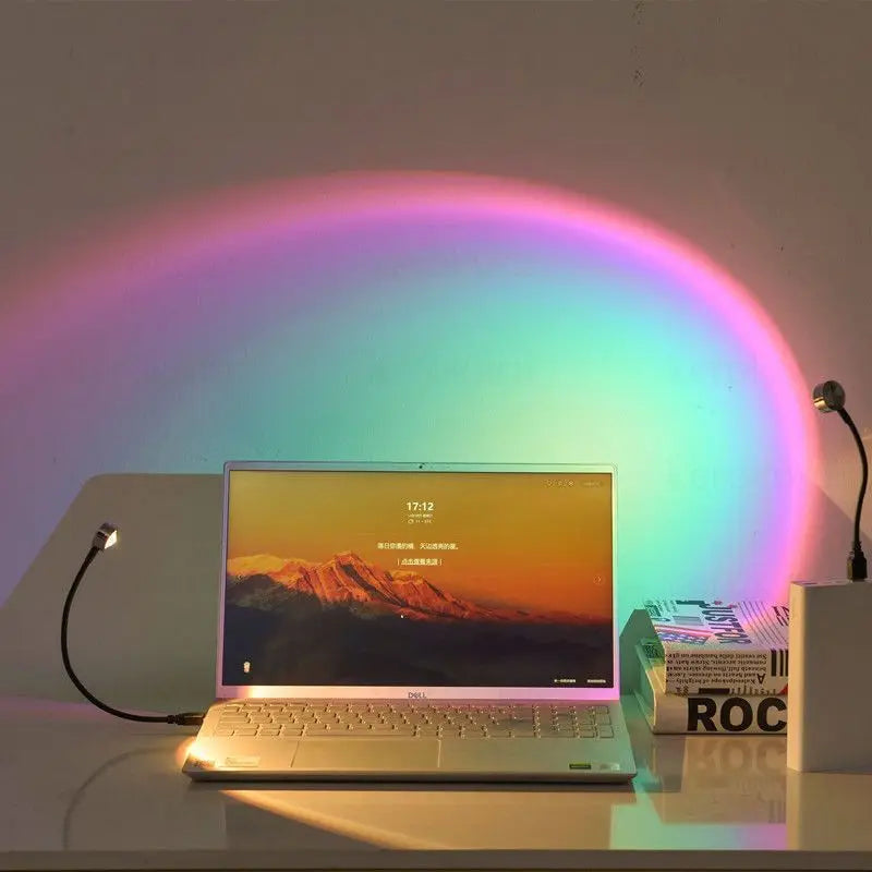 A laptop displaying a sunset projection light onto the screen, casting colorful light onto the background.