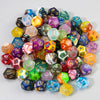 A collection of ten polyhedral dice in various colors and shapes scattered on a white surface.
