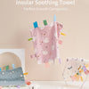 A pink baby sensory tag comfort blanket with white swan designs and a soothing teether hanging on a wall.