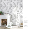 A white fireplace mantel decorated with a Boho Leaf Peel-and-Stick wallpaper featuring green and white floral designs on the 