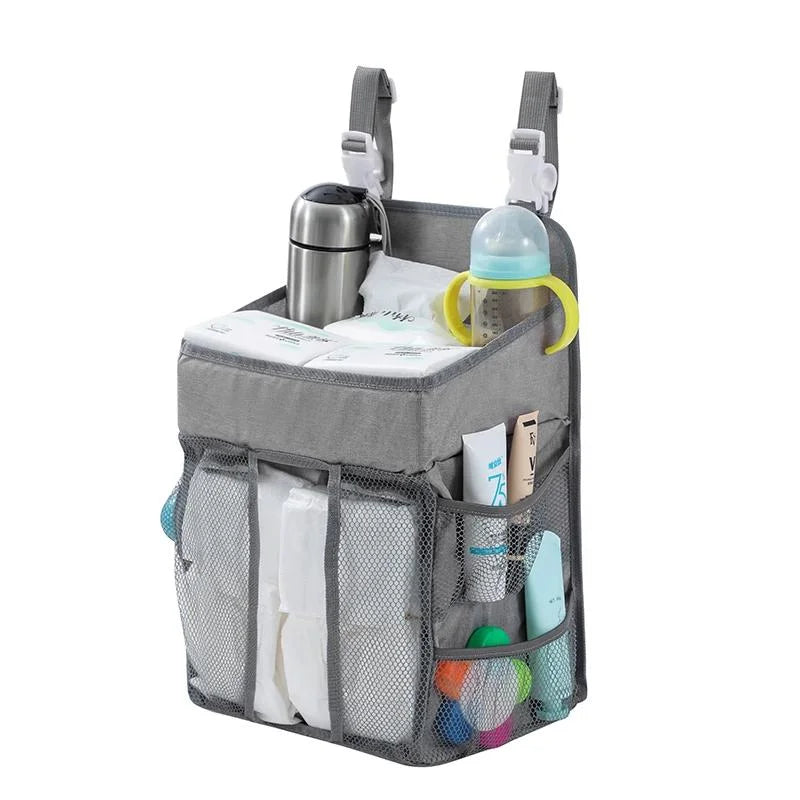 A gray hanging diaper storage organizer with multiple mesh pockets and a stainless steel bottle holder.