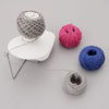 A collection of hand-spun yarn balls in various colors and textures, including gray, pink, and blue, displayed on a light sur