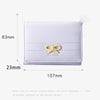 A white tri-fold wallet featuring a gold bow design, shown with dimensions of 83mm by 107mm.