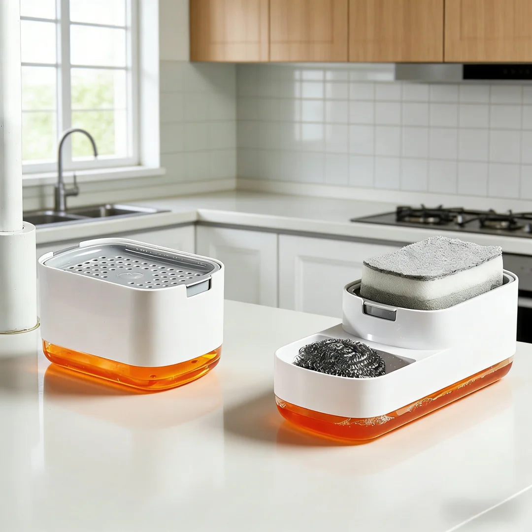 A white countertop soap dispenser with an orange base and a built-in sponge holder sits on a white kitchen counter.