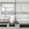 A modern bathroom featuring a toilet, sink area, and a white bathtub with black non-slip bath mats.