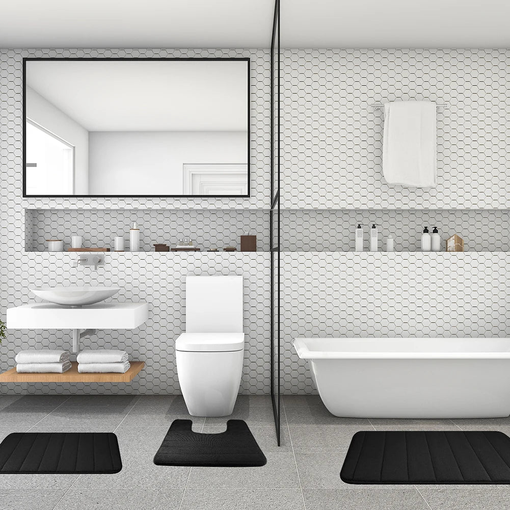A modern bathroom featuring a toilet, sink area, and a white bathtub with black non-slip bath mats.