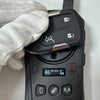 A hand wearing a white glove holds a black replacement remote key for a vehicle.