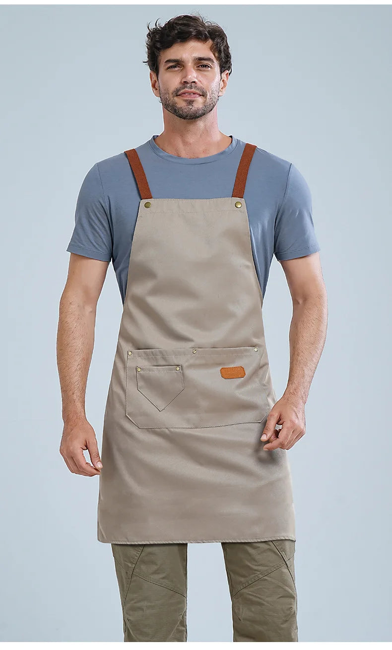 A man wearing a beige waterproof kitchen apron over a blue t-shirt and olive green pants.